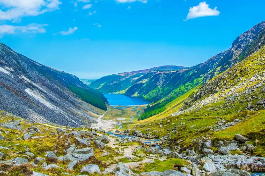 Aerial view of Glendalough in County Wicklow, Ireland, featuring the upper and lower lakes surrounded by lush green valleys, rocky hills, and scenic mountain landscapes popular with tourists and hikers