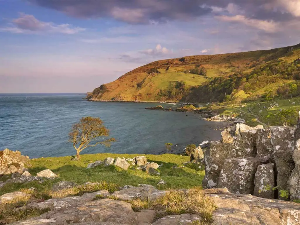 Scenic view of Murlough Bay in Northern Ireland with rugged coastline, green hills, and rocky cliffs, a famous Game of Thrones filming location and popular Irish tourist attraction