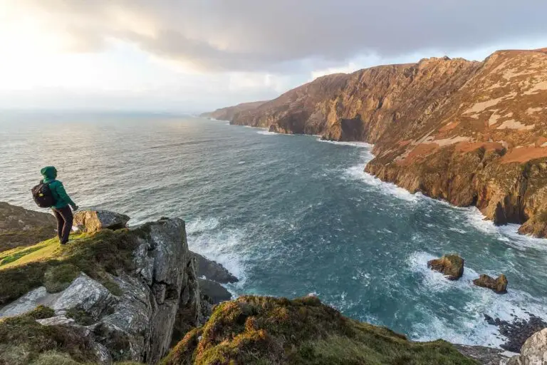 Tourist standing on cliff overlooking dramatic ocean views at Slieve League, Ireland