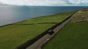 Luxury tour van driving along the scenic Ring of Kerry coastline in Ireland with green fields and ocean views