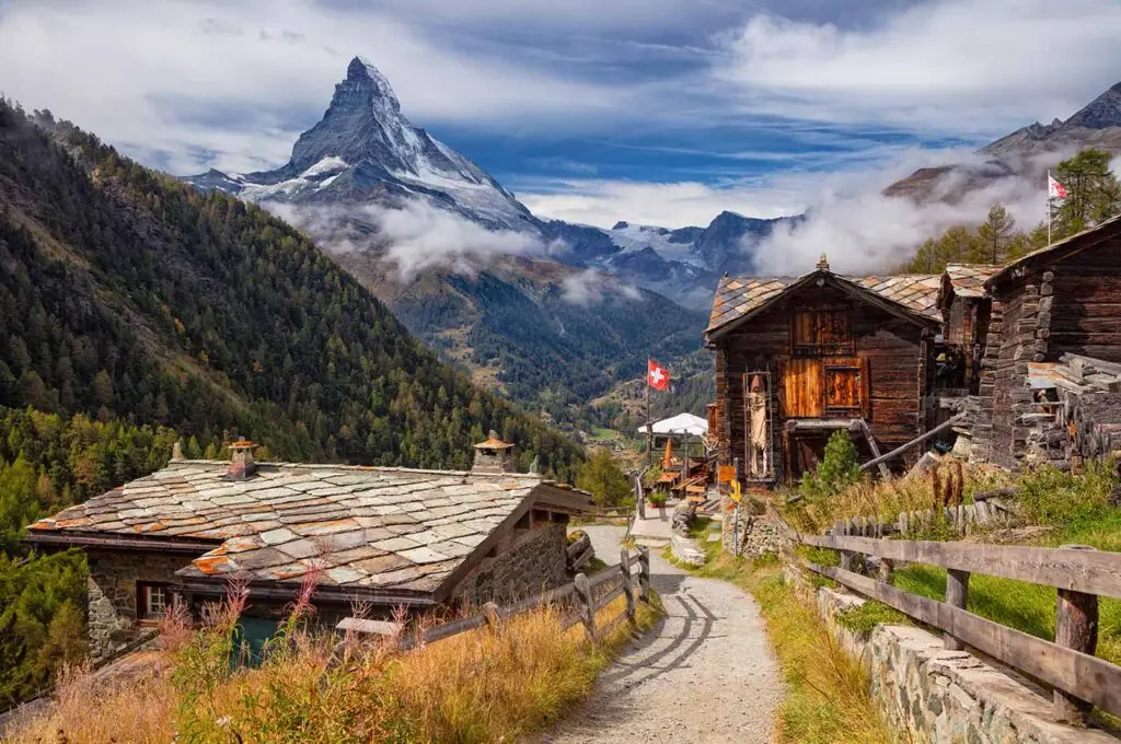 Scenic view of the Matterhorn mountain and traditional wooden chalets in Zermatt Switzerland with Swiss flags and alpine landscape on a clear sunny day