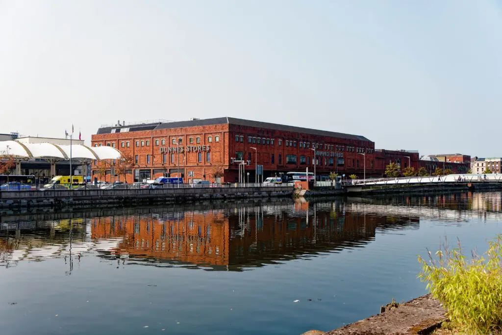 Scenic waterfront view of Cork City Ireland featuring red brick Dunnes Stores building and reflections on the River Lee