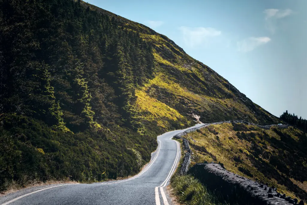 Winding mountain road through the scenic green hills of Sally Gap, County Wicklow, Ireland, on a sunny day with stunning natural landscape views