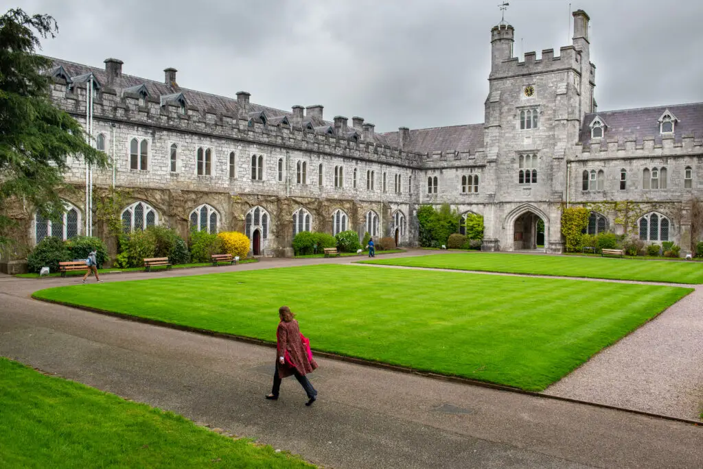 Historic courtyard and gothic architecture of University College Cork in Cork, Ireland, featuring lush green lawns and stone buildings popular with tourists and students