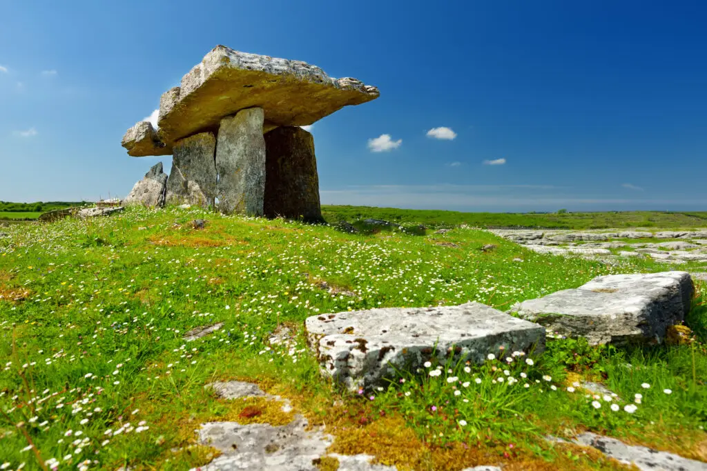 Poulnabrone Dolmen ancient stone tomb in the Burren, County Clare, Ireland surrounded by green grass and blue sky, popular Irish tourist attraction