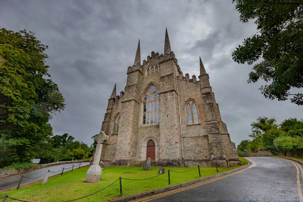 Down Cathedral in Northern Ireland with Gothic architecture and Celtic cross on a cloudy day, a historic Christian landmark and popular tourism site in Downpatrick