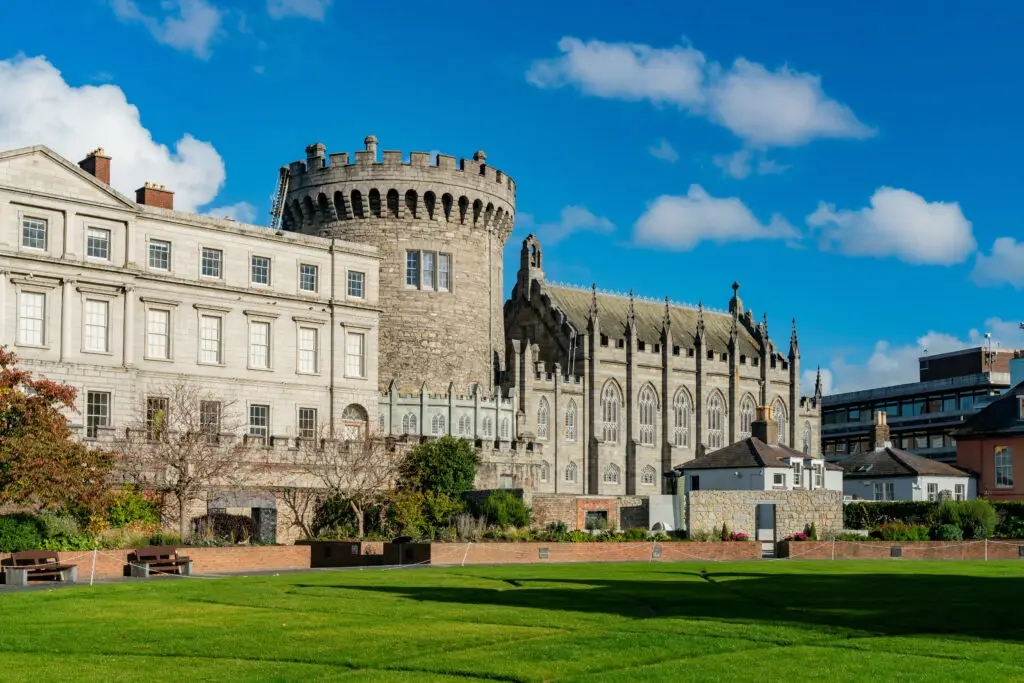 Dublin Castle in Ireland with historic stone architecture and landscaped gardens under a bright blue sky, a popular tourist attraction and landmark in Dublin City