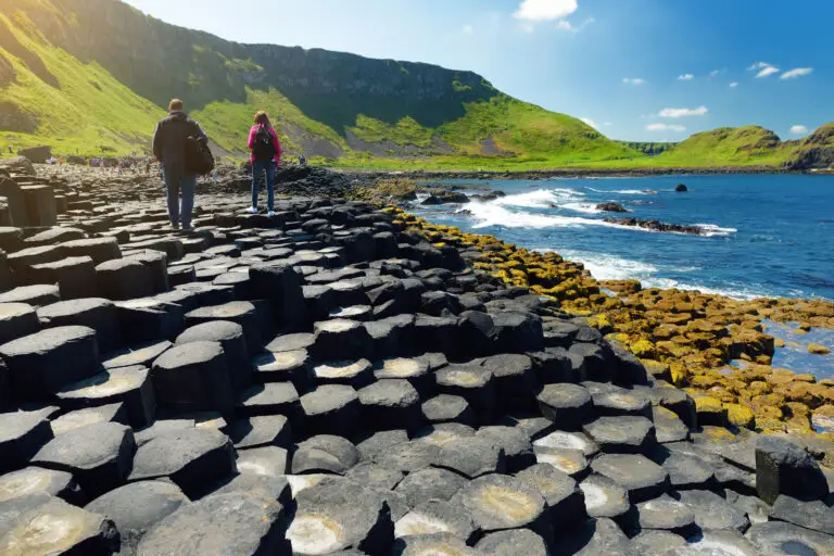 Tourists walking along the basalt columns at the Giant’s Causeway, a famous UNESCO World Heritage Site on the coast of Northern Ireland with scenic cliffs and ocean views