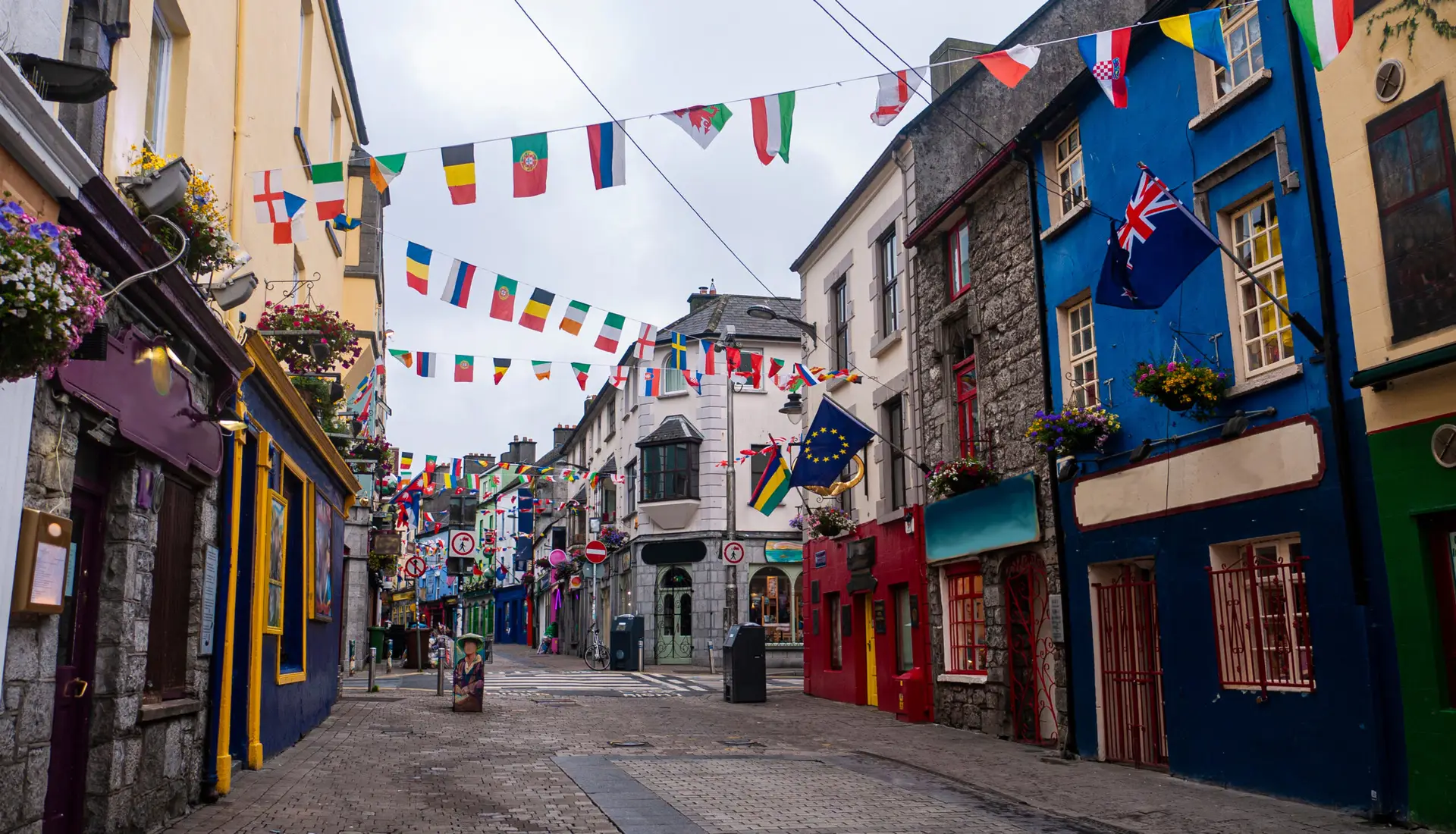 Colorful street with hanging flags and traditional Irish buildings in Galway City, Ireland, showcasing vibrant architecture and a popular tourist attraction