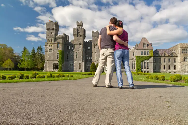 Couple embracing while admiring Ashford Castle in Ireland, highlighting romantic Irish castle tours and luxury travel experiences