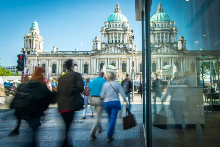 Tourists walking past Belfast City Hall, a historic landmark and popular attraction in Belfast, Northern Ireland