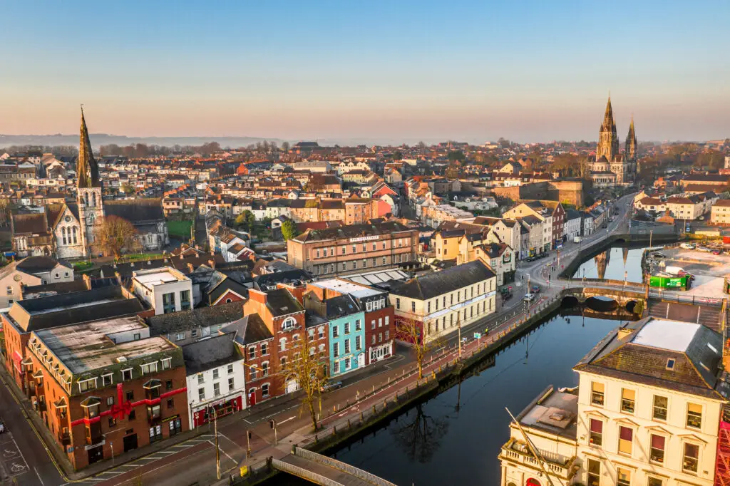 Aerial view of Cork City Ireland showing colorful riverside buildings, historic churches, and scenic cityscape at sunrise