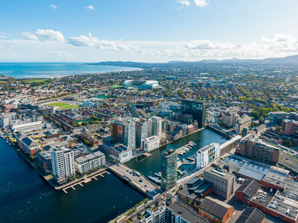 Aerial view of Dublin city, Ireland featuring modern architecture, Grand Canal Dock, and the coastline on a sunny day