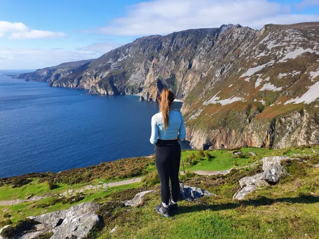 Tourist admiring the dramatic sea cliffs at Slieve League, County Donegal, Ireland, with panoramic coastal views and rugged mountain scenery