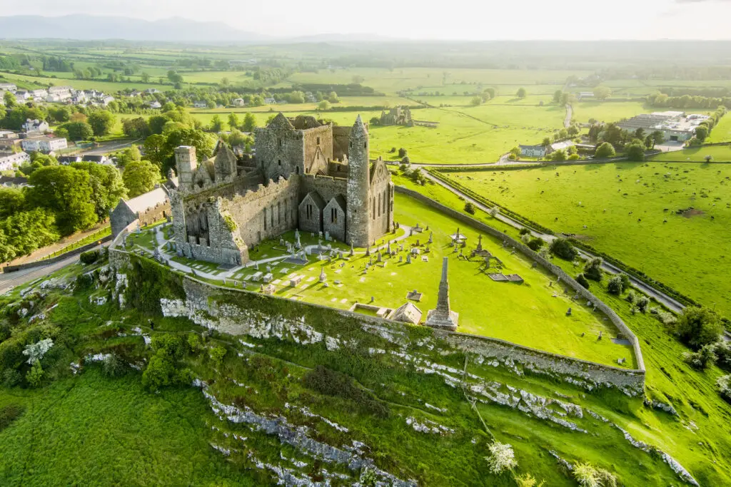Aerial view of the Rock of Cashel in County Tipperary, Ireland, showing the ancient castle ruins and surrounding green countryside, a popular tourist attraction on Ireland luxury tours.