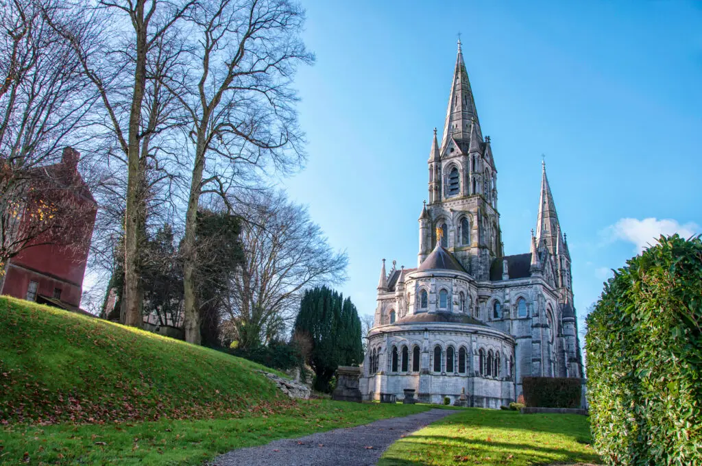 St Fin Barre's Cathedral in Cork Ireland surrounded by gardens and trees on a bright sunny day
