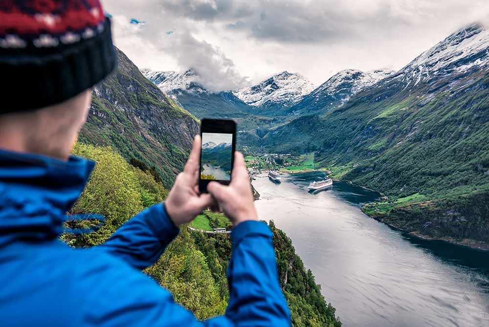 Scenic view of Norway Fjord with tourist in the foreground taking an image from a mountain viewpoint