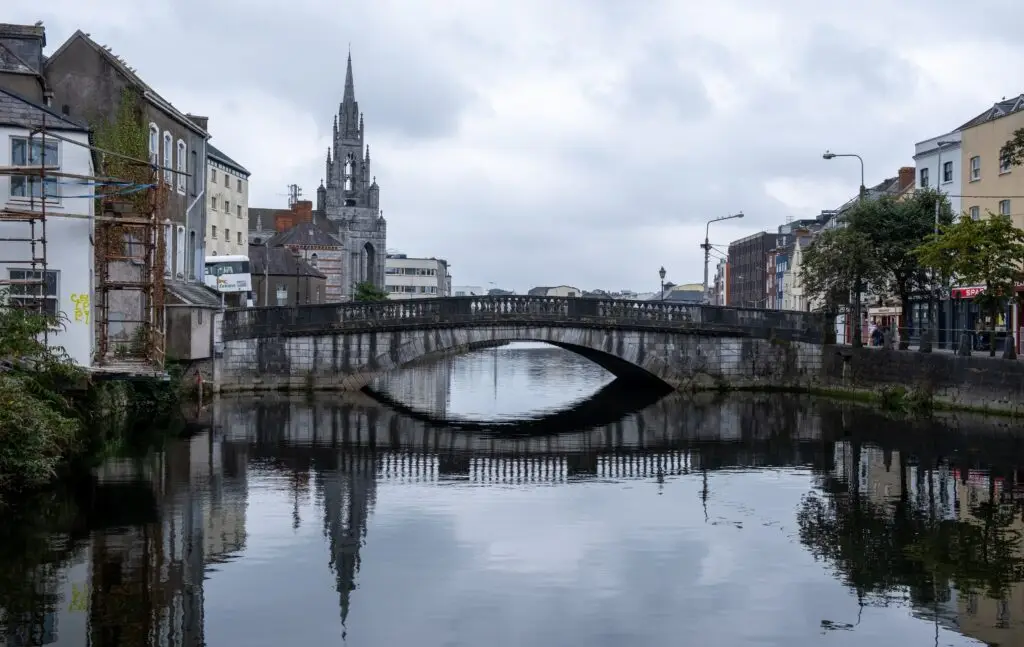 Historic bridge over the River Lee with city buildings and church spire in Cork, Ireland