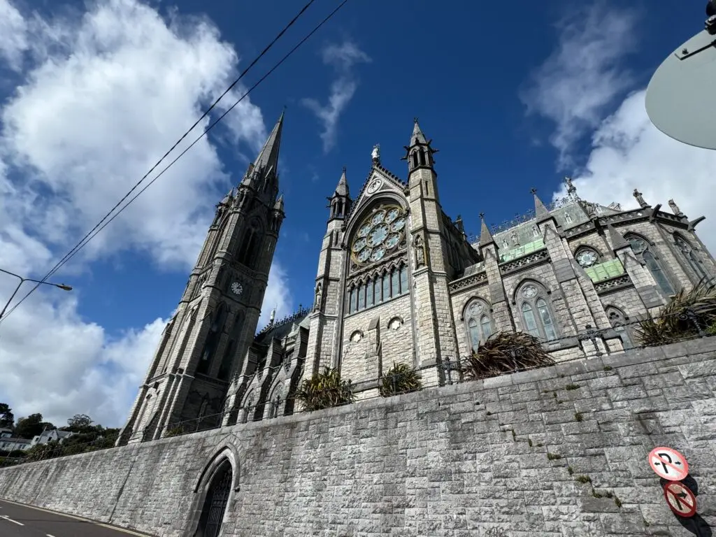 St. Colman’s Cathedral in Cobh, Ireland, with its tall spire and detailed Gothic architecture under a bright blue sky, a popular tourist attraction on the southern coast of Ireland